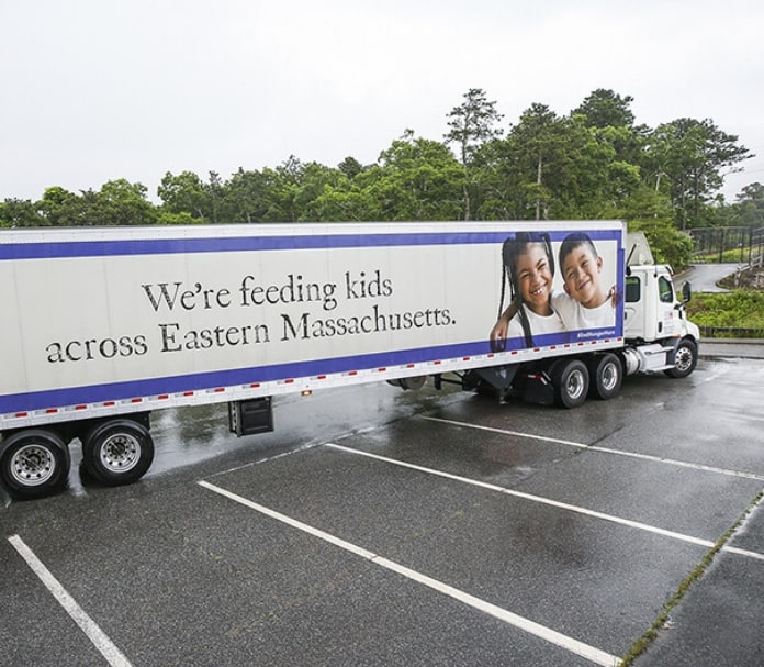 A Tractor Trailer with the words 'We are feeding kids across Eastern Massachusetts' is written on its side.